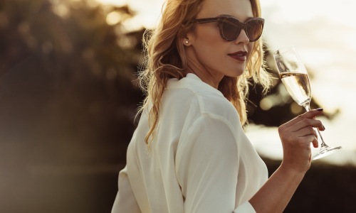 a woman sipping on wine outdoors in a bright dress