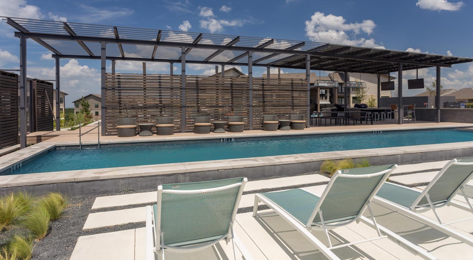 Relax and unwind poolside a pool with chairs around it